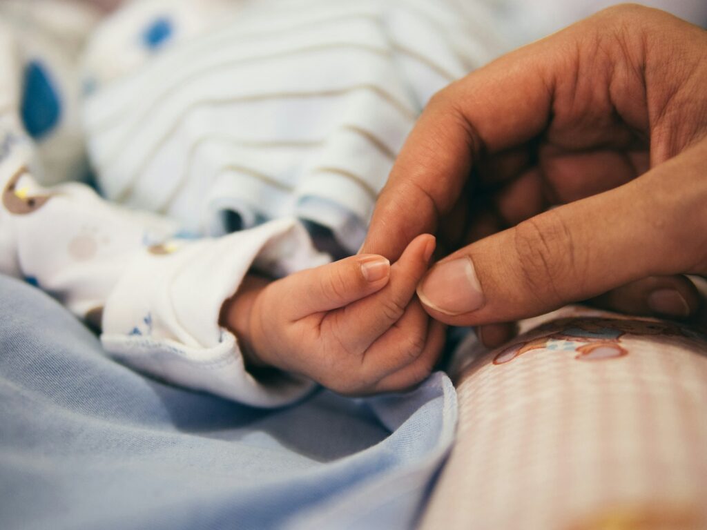 Adulto a segurar o dedo indicador de um bebé recém-nascido
