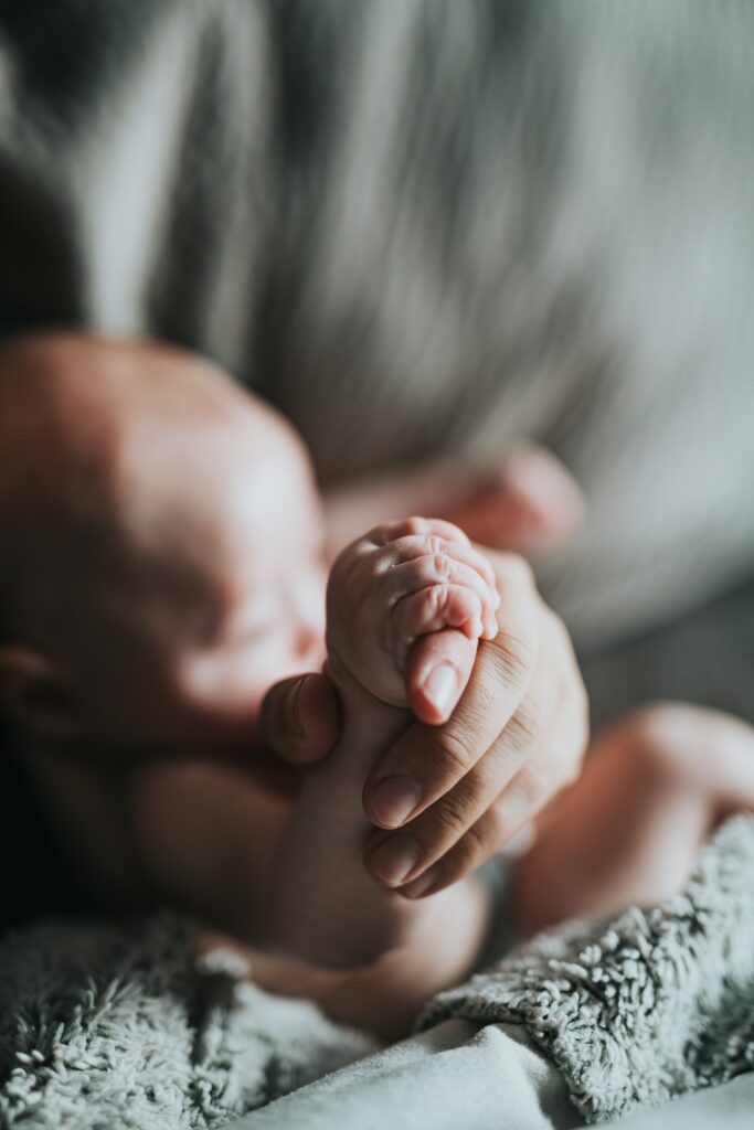 Mãozinha de bebé recém-nascido na mão de um adulto