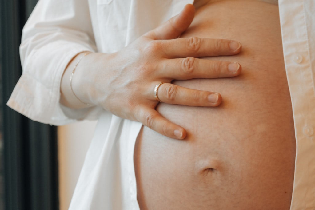 Barriga de grávida com uma mão pousada sobre ela