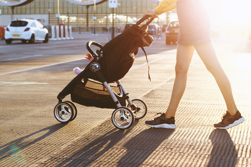 Mãe a passear na rua com o bebé no carrinho, ao fim da tarde